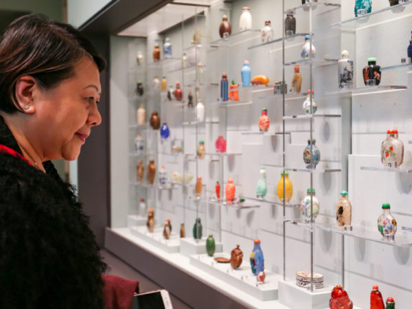 A woman looks at a display case full of small, colorful snuff bottles.
